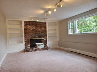 Remodeled basement with new windows, shelves, walls, and a fireplace in the middle of the room