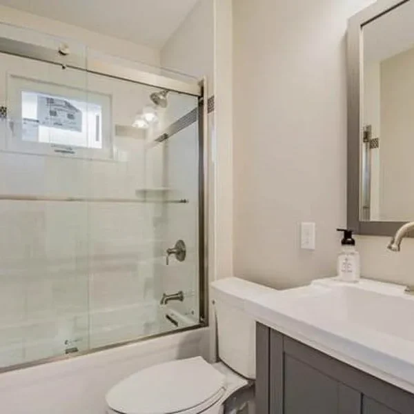 Bathroom remodel with gray vanity and glass tub-shower