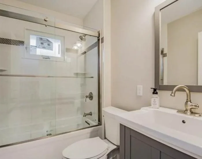 Bathroom remodel with gray vanity and glass tub-shower