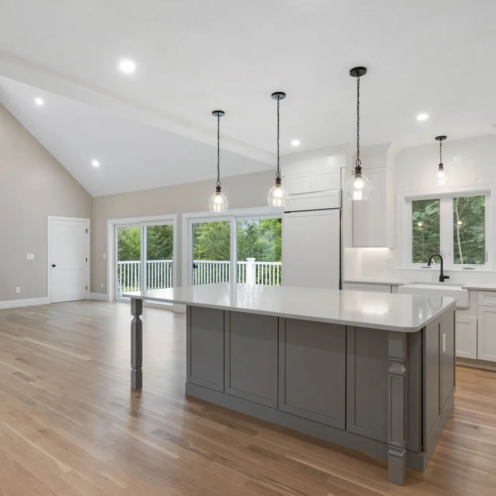 Open-concept white kitchen with gray island and living area