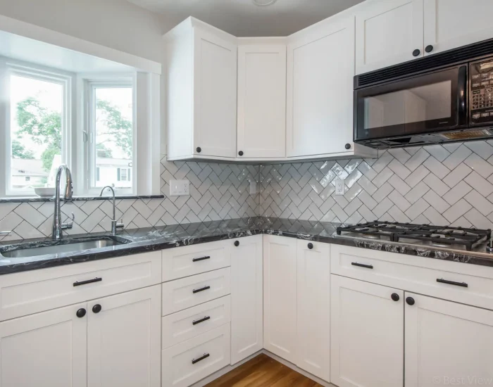 White shaker kitchen with black counters and bay-window sink