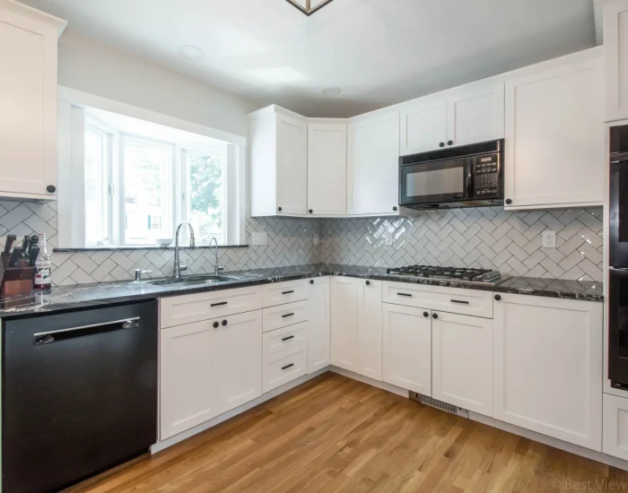 White shaker kitchen with herringbone backsplash and bay window
